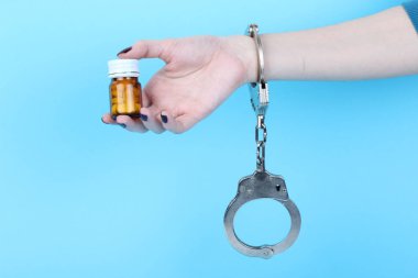 Mavi arka planda elleri kelepçeli haplar ve tabletler