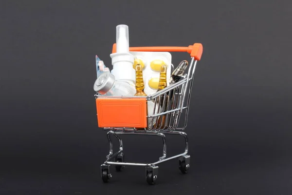 Shopping trolley with pills and medicine isolated on black