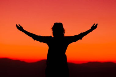 Gün batımında kollarını kaldırdı, yüksek enerjili kadın.