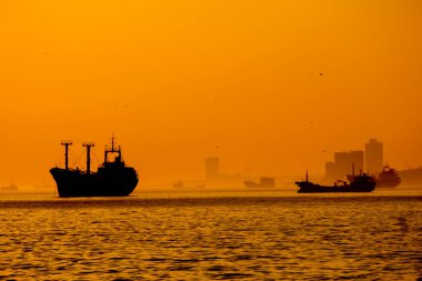 Kargo gemisi batan güneşin ışınlarında denizde..