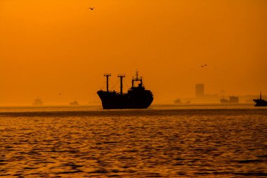 Kargo gemisi batan güneşin ışınlarında denizde..