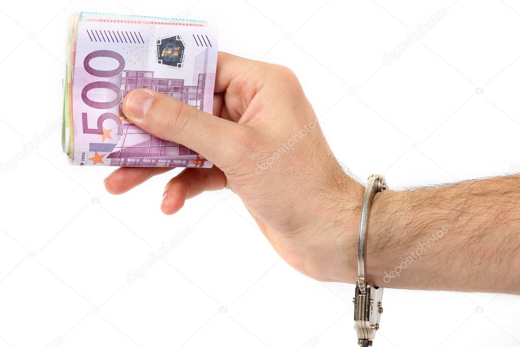 Male hand with handcuffs holding a lot of money