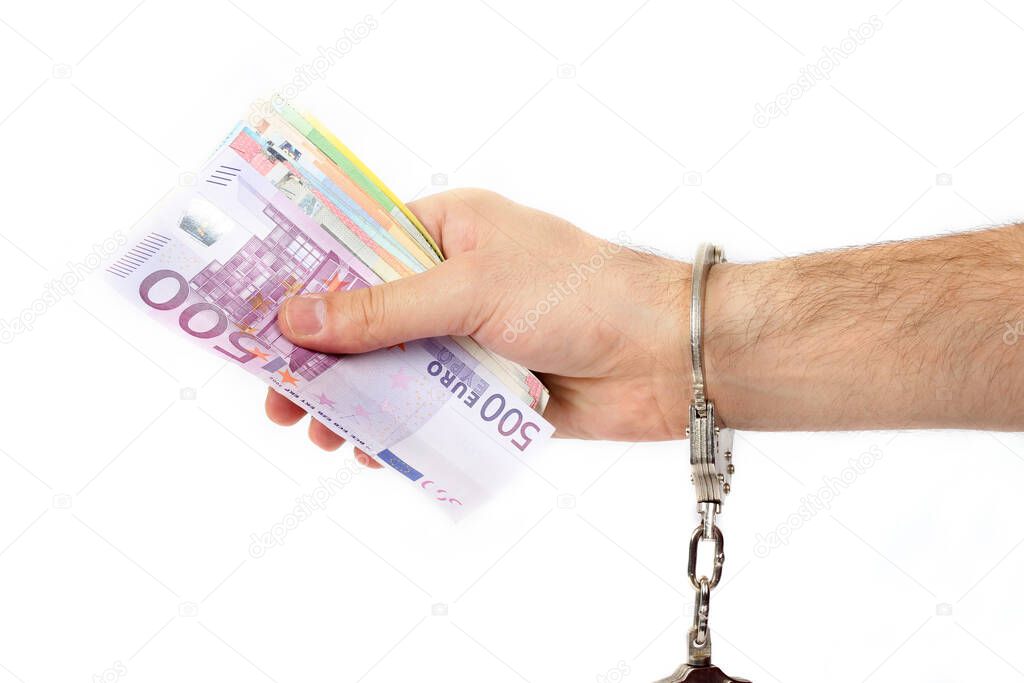 Male hand with handcuffs holding a lot of money