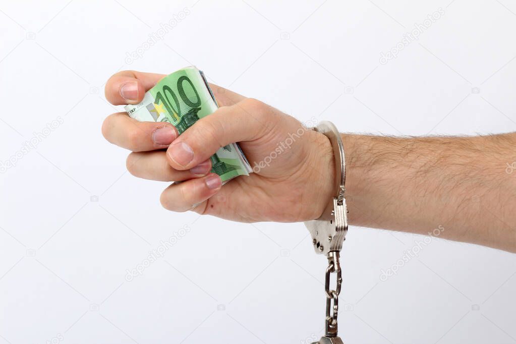 Male hand with handcuffs holding a lot of money