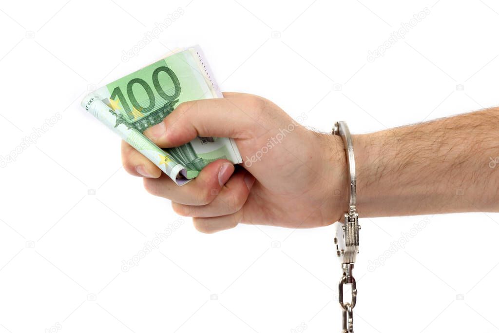 Male hand with handcuffs holding a lot of money