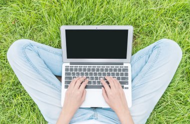 Asyalı kadın bir dizüstü bilgisayar, iş kavramı, Açık Bahçe dokulu arka planda kullanım için çim katta oturan