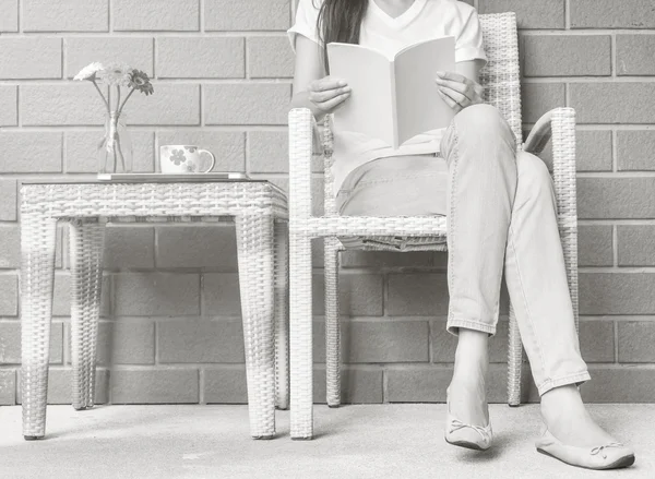 Woman sitting on wood weave chair in house for reading a white book in free time in the afternoon , relax time and lifestyle of asian woman concept in black and white tone — Stock Photo, Image