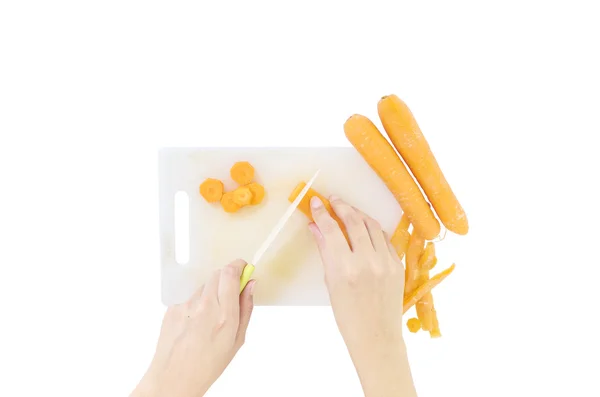 Primer plano pila fresca de zanahoria y cáscara de zanahoria con cuchillo en la mano de la mujer en el viejo tablero de corte de plástico blanco aislado sobre fondo blanco, prepararse para el concepto de cocinero — Foto de Stock