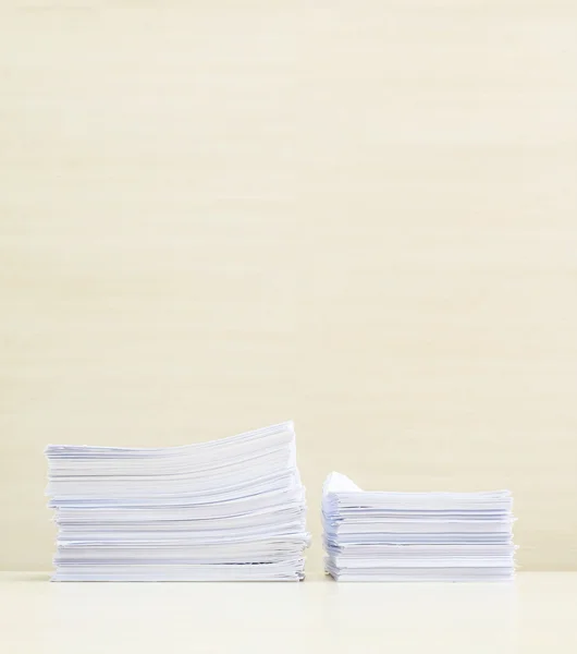 Closeup pile of work paper on blurred wooden desk and wall textured background in the meeting room under window light , hard work concept with copy space