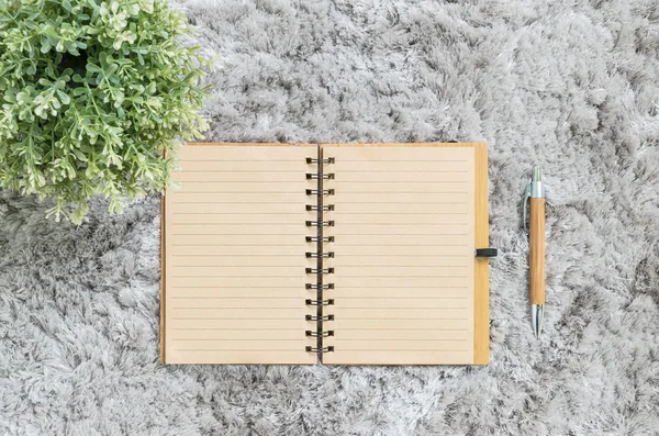 Nahaufnahme braunes Notizbuch mit braunem Stift auf grauem Stoffcapet mit strukturiertem Hintergrund — Stockfoto