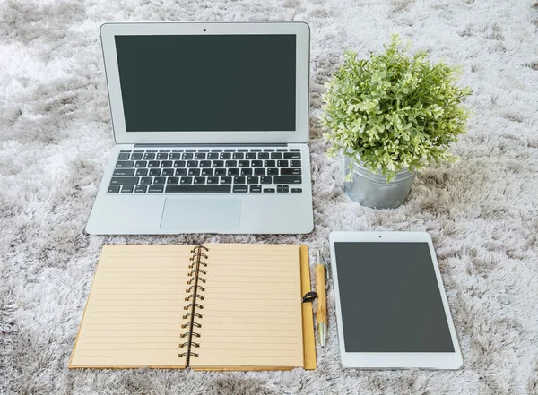 Closeup hnědá kniha poznámek, hnědé pero, počítačový notebook, tabletové a umělé rostliny na šedé tkaniny tapet s texturou — Stock fotografie