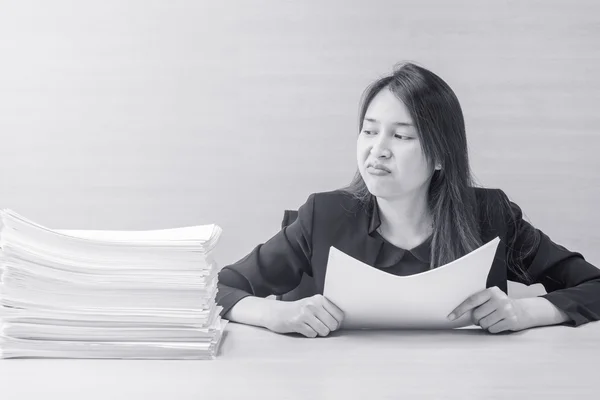 Primo piano donna che lavora sono noiosi da mucchio di carta da lavoro di fronte a lei nel concetto di lavoro su scrivania in legno sfocato e parete in legno sfondo strutturato nella sala riunioni sotto la luce della finestra — Foto Stock