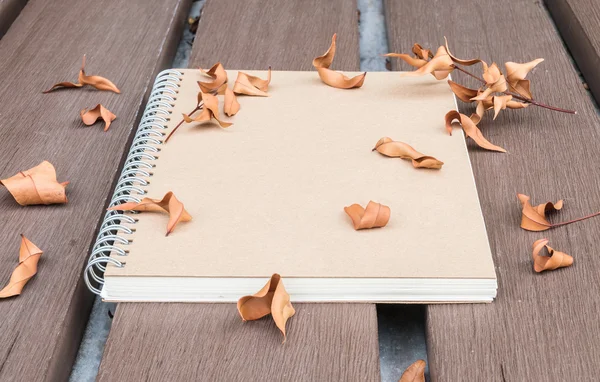 Närbild bruna anteckningsbok på träbord i trädgården med torkade blad texturerat bakgrund — Stockfoto