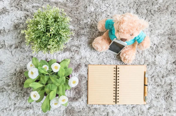 Closeup diário livro nota marrom com linha na página com caneta marrom com planta artificial e urso boneca no chão tapete cinza fundo texturizado — Fotografia de Stock