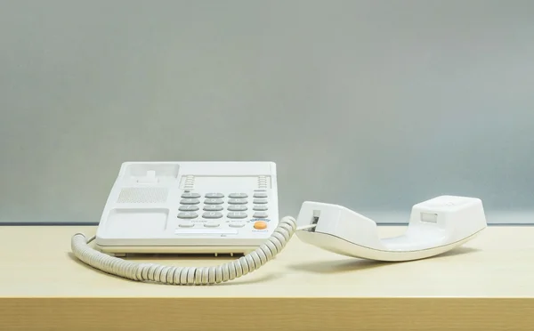 Zbliżenie telefonu, telefon na biurko z drewna niewyraźne białe i matowe szklane ściany teksturowanej tło w urzędzie pracy — Zdjęcie stockowe