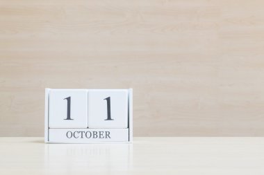 Dolap yüzeyi beyaz ahşap takvim siyah 11 ekim kelime ile bulanık kahverengi ahşap masa ve ahşap duvar kopya alanı ile dokulu arka plan , benim portföyünde başka bir tarih görünümü