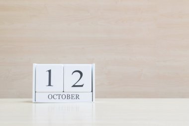 Dolap yüzeyi beyaz ahşap takvim siyah 12 ekim kelime ile bulanık kahverengi ahşap masa ve ahşap duvar kopya alanı ile dokulu arka plan , benim portföyünde başka bir tarih görünümü