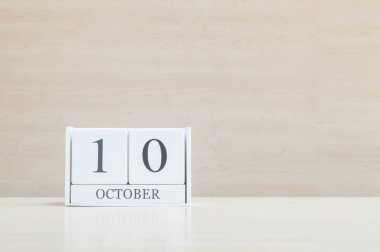 Dolap yüzeyi beyaz ahşap takvim siyah 10 ekim kelime ile bulanık kahverengi ahşap masa ve ahşap duvar kopya alanı ile dokulu arka plan , benim portföyünde başka bir tarih görünümü