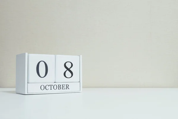 Closeup surface white wooden calendar with black 8 october word on blurred white wood desk and cream color wallpaper in room textured background with copy space — Stock Photo, Image