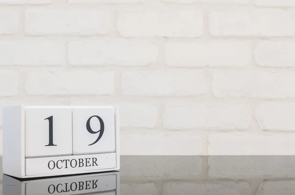 Крупный план белый деревянный календарь с черным 19 октября слово на черном стеклянном столе и белой кирпичной стены текстурированный фон с копировальным пространством, просмотреть еще одну дату в моем портфолио — стоковое фото