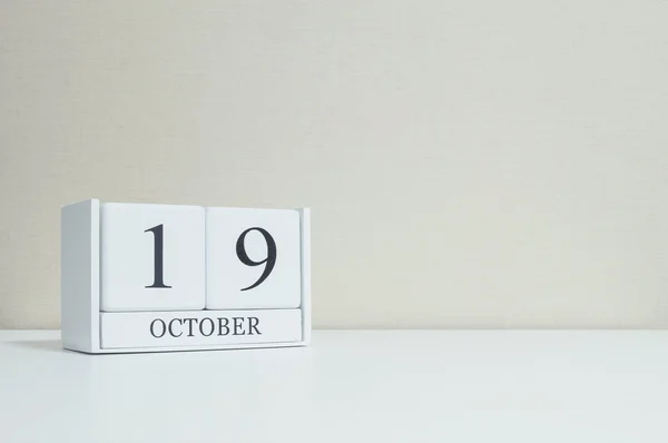 Primer plano calendario de madera blanca con negro 19 palabra de octubre en escritorio de madera blanca borrosa y fondo de pantalla de color crema en el fondo de textura de la habitación con espacio de copia, ver otra fecha más en mi cartera — Foto de Stock