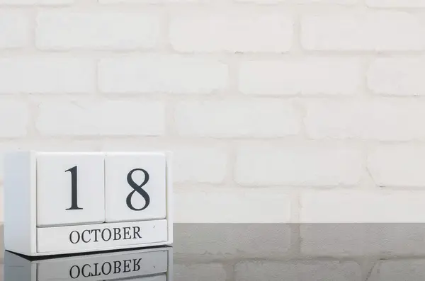 Primer plano calendario de madera blanca con negro 18 palabra de octubre en mesa de vidrio negro y pared de ladrillo blanco fondo texturizado con espacio de copia, ver otra fecha más en mi cartera — Foto de Stock