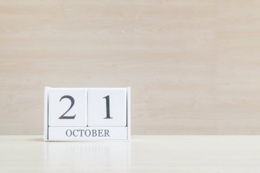 Kapalı yüzey beyaz ahşap takvim, siyah 21 Ekim tarihinde bulanık kahverengi ahşap masa ve ahşap duvar, fotokopi alanı ile desenli arka plan, takvimde seçici odak