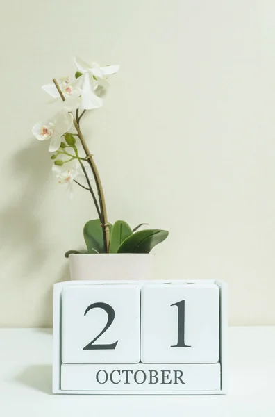 Closeup calendário de madeira branco com preto 21 palavra de outubro com flor de orquídea branca na mesa de madeira branca e papel de parede cor creme no quarto fundo texturizado, foco seletivo no calendário — Fotografia de Stock