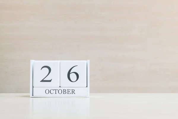 Primer plano de la superficie del calendario de madera blanca con negro 26 palabra de octubre en borrosa escritorio de madera marrón y fondo texturizado pared de madera con espacio de copia, enfoque selectivo en el calendario — Foto de Stock