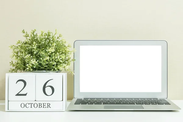 Calendario de madera blanca con negro 26 palabra de octubre con espacio en blanco en el centro de la computadora portátil en escritorio de madera blanca y fondo de pantalla crema texturizado, enfoque selectivo en el calendario — Foto de Stock