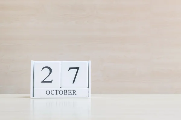 Closeup επιφάνεια λευκό ξύλινο ημερολόγιο με μαύρο 27 οκτάμπερ λέξη για θολή καφέ γραφείο ξύλο και ξύλο τοίχο υφή φόντο με αντίγραφο χώρο, επιλεκτική εστίαση στο ημερολόγιο — Φωτογραφία Αρχείου