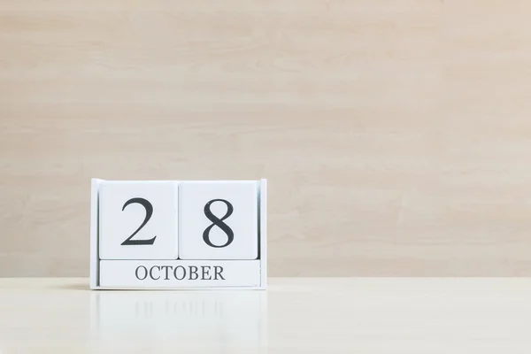 Primer plano de la superficie del calendario de madera blanca con negro 28 palabra de octubre en borrosa escritorio de madera marrón y fondo texturizado pared de madera con espacio de copia, enfoque selectivo en el calendario — Foto de Stock