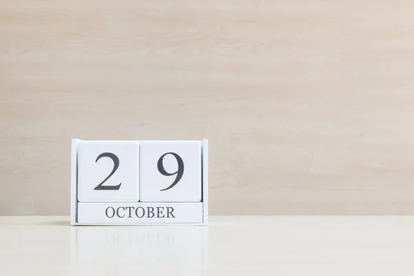 Primer plano de la superficie del calendario de madera blanca con negro 29 palabra de octubre en borrosa escritorio de madera marrón y fondo texturizado pared de madera con espacio de copia, enfoque selectivo en el calendario — Foto de Stock