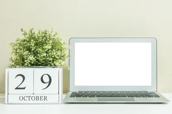 Calendario de madera blanca con negro 29 palabra de octubre con espacio en blanco en el centro de la computadora portátil en escritorio de madera blanca y fondo de pantalla crema texturizado, enfoque selectivo en el calendario — Foto de Stock