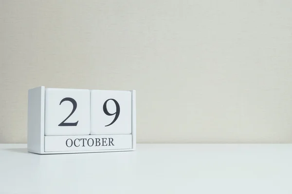 Closeup calendário de madeira branca com preto 29 palavra outubro na mesa de madeira branca borrada e papel de parede cor creme no quarto fundo texturizado com espaço de cópia, foco seletivo no calendário — Fotografia de Stock