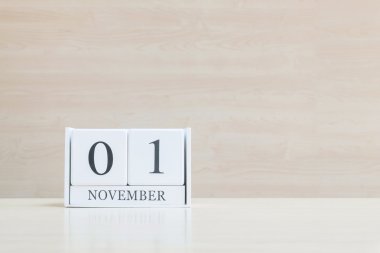 Closeup bulanık kahverengi ahşap masa ve kopya alanı, takvim, seçici odak ile ahşap duvar dokulu arka plan üzerinde siyah 1 Kasım kelime ile beyaz ahşap takvim yüzey