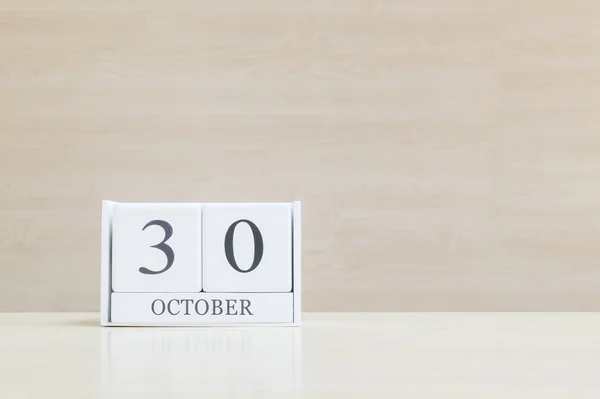 Closeup surface white wooden calendar with black 30 october word on blurred brown wood desk and wood wall textured background with copy space , selective focus at the calendar — Φωτογραφία Αρχείου
