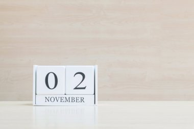 Closeup bulanık kahverengi ahşap masa ve kopya alanı, takvim, seçici odak ile ahşap duvar dokulu arka plan üzerinde siyah 2 Kasım kelime ile beyaz ahşap takvim yüzey
