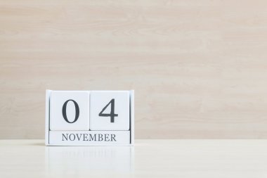Closeup bulanık kahverengi ahşap masa ve kopya alanı, takvim, seçici odak ile ahşap duvar dokulu arka plan üzerinde siyah 4 Kasım kelime ile beyaz ahşap takvim yüzey