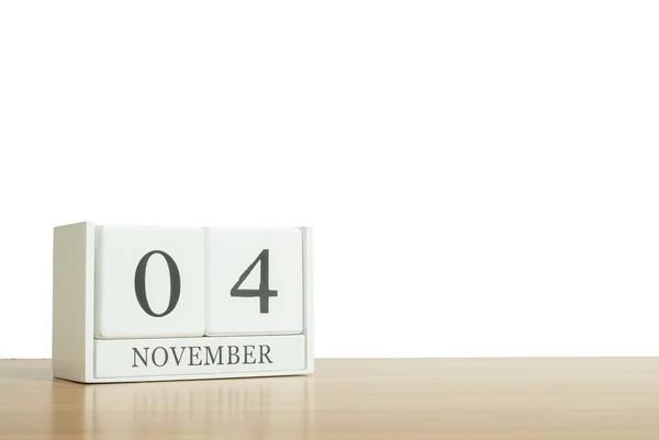 Närbild yta vit trä kalender svart 4 november ord om suddig brun trä skrivbord isolerade på vit bakgrund med kopia utrymme, selektivt fokus på kalendern — Stockfoto