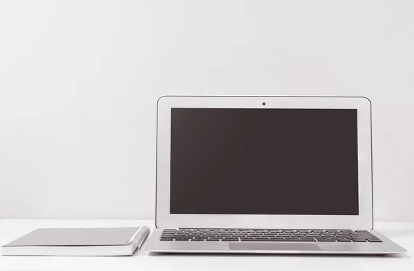 Крупним планом комп'ютерний ноутбук на розмитому білому дерев'яному столі та шпалерах кремового кольору на фоні текстури кімнати, красиве робоче місце інтер'єру концепції будинку в чорно-білому тоні — стокове фото