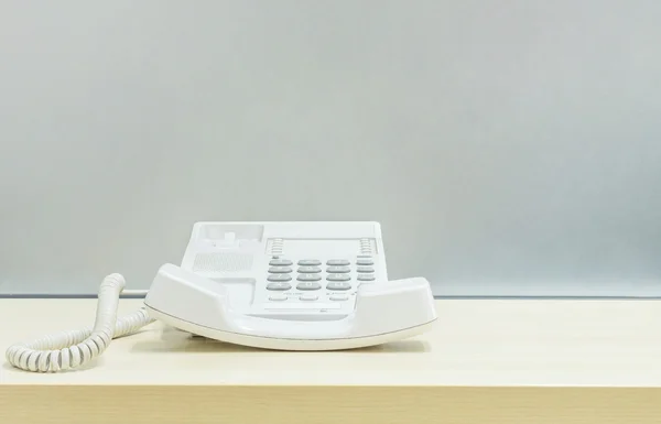 Closeup telefone branco, telefone de escritório na mesa de madeira borrada e parede de vidro fosco texturizado fundo no escritório de trabalho — Fotografia de Stock