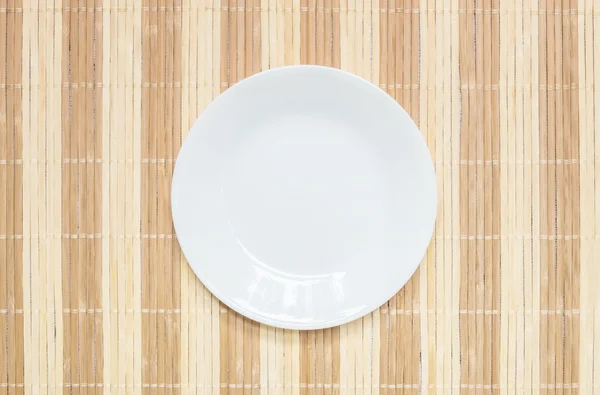 Closeup white ceramic dish on wood mat textured background at the center on dining table in top view with copy space — Stock Photo, Image