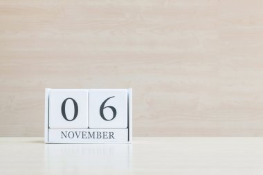 Closeup bulanık kahverengi ahşap masa ve kopya alanı, takvim, seçici odak ile ahşap duvar dokulu arka plan üzerinde siyah 6 Kasım kelime ile beyaz ahşap takvim yüzey