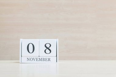 Closeup bulanık kahverengi ahşap masa ve kopya alanı, takvim, seçici odak ile ahşap duvar dokulu arka plan üzerinde siyah 8 Kasım kelime ile beyaz ahşap takvim yüzey