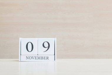 Closeup bulanık kahverengi ahşap masa ve kopya alanı, takvim, seçici odak ile ahşap duvar dokulu arka plan üzerinde siyah 9 Kasım kelime ile beyaz ahşap takvim yüzey