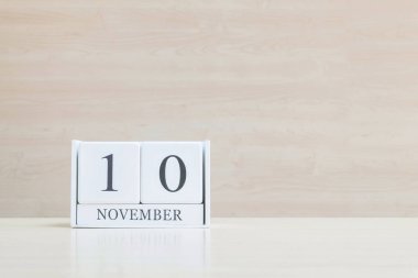 Closeup bulanık kahverengi ahşap masa ve kopya alanı, takvim, seçici odak ile ahşap duvar dokulu arka plan üzerinde siyah 10 Kasım kelime ile beyaz ahşap takvim yüzey