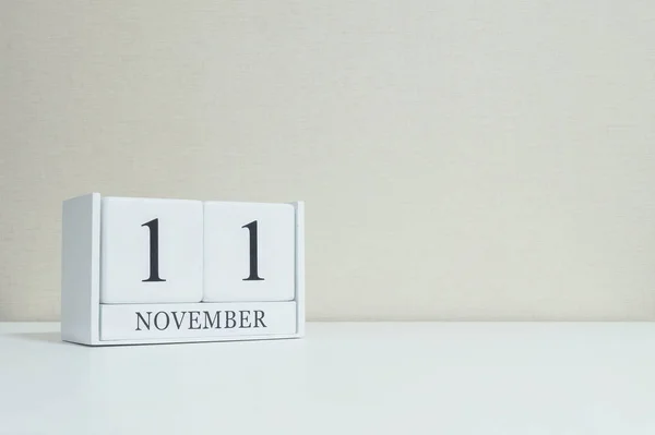 Gros plan calendrier en bois blanc avec noir 11 Novembre mot sur le bureau en bois blanc flou et papier peint de couleur crème dans la chambre fond texturé avec espace de copie, mise au point sélective au calendrier — Photo