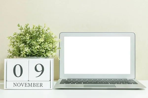 Білий дерев'яний календар з чорним 9 листопада слово з білим порожнім простором в центрі комп'ютерного ноутбука на білому дерев'яному столі і кремових шпалерах текстурованого фону, вибірковий фокус на календарі — стокове фото