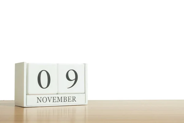 Nahaufnahme Oberfläche weißer Holzkalender mit schwarzem 9. November Wort auf unscharfem braunem Holz Schreibtisch isoliert auf weißem Hintergrund mit Kopierraum, selektiver Fokus auf den Kalender — Stockfoto